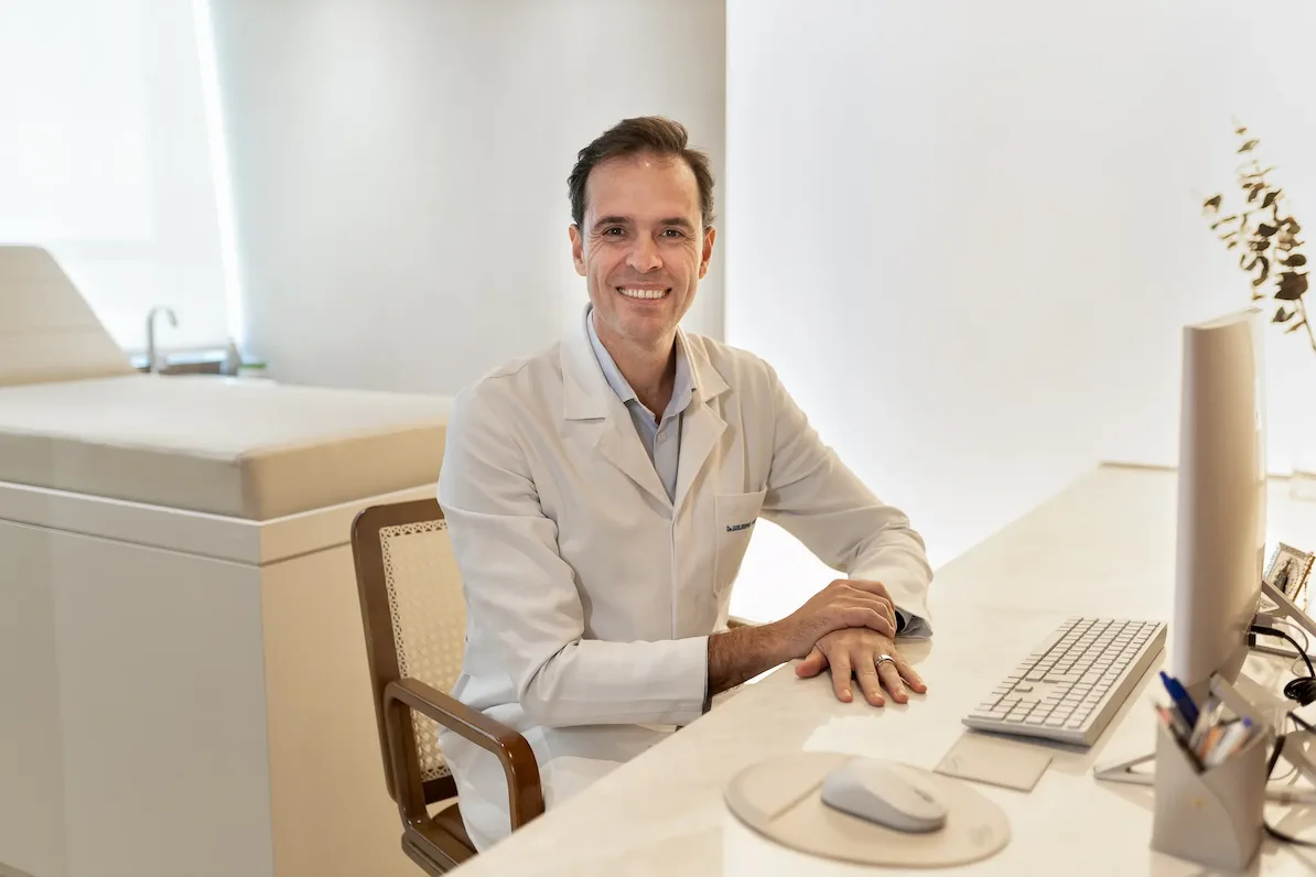 Dr. Guilherme Marquezine de jaleco branco no consultório